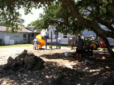 Principal Padgett poses in the shade with his shovel as he helps dismantle the old playground equipment on a extremely hot day. 